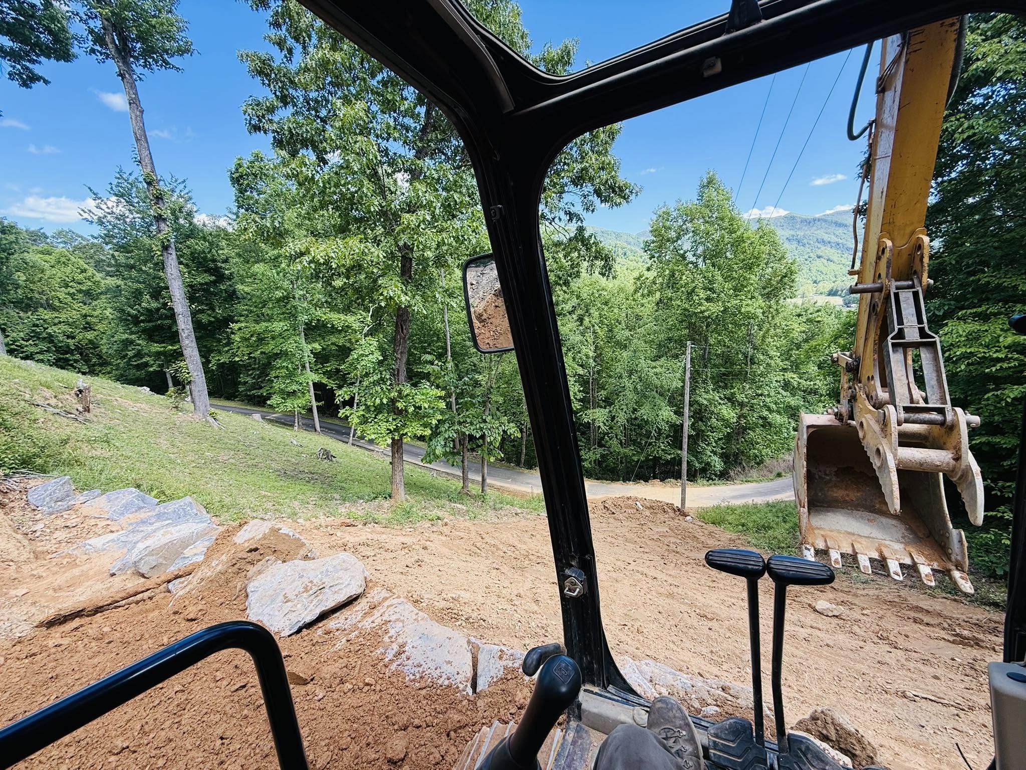 Excavator placing boulders and grading a commercial site in Western North Carolina