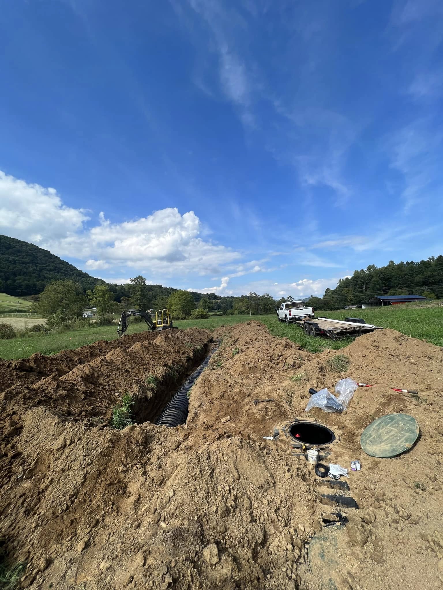 Drainage line trenched across a field with septic riser set, Western NC