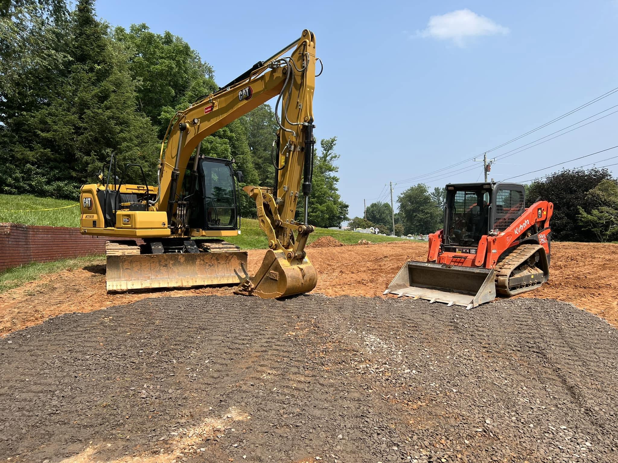 Excavator and skid steer staged on a graded gravel pad